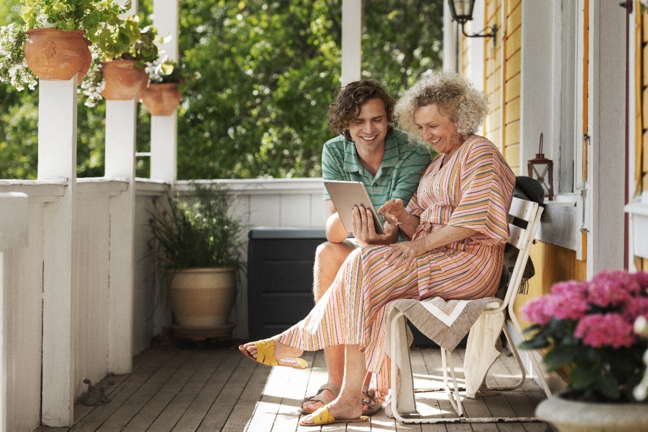 Mother and adult son looking at a laptop on the porch